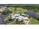 Aerial view of the clubhouse featuring the parking lot, pool, golf course, and lake at 707 Petrel Way, Venice, FL 34285