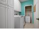 Bright laundry room with white cabinetry, modern washer/dryer, and utility sink at 707 Petrel Way, Venice, FL 34285