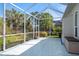 View of screened-in patio with tile flooring and tropical foliage beyond at 707 Petrel Way, Venice, FL 34285
