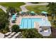 Overhead shot of a community pool with lounge chairs, tables, umbrellas, and golf course in the background at 707 Petrel Way, Venice, FL 34285