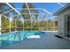 Backyard pool area featuring screened-in enclosure, trees, and partial outdoor shower at 707 Petrel Way, Venice, FL 34285