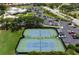 Aerial shot of tennis courts, landscaping, parking area, and the buildings in the community at 707 Petrel Way, Venice, FL 34285