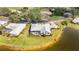 Aerial view of a lakeside home featuring a screened lanai, lush landscaping and a barrel tile roof at 803 Carnoustie Dr, Venice, FL 34293