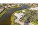Aerial view of home with paved driveway, screened lanai, and lush landscaping by the lake at 803 Carnoustie Dr, Venice, FL 34293