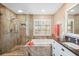 Elegant bathroom featuring a large soaking tub, granite counters, updated vanity and a glass enclosed shower at 803 Carnoustie Dr, Venice, FL 34293