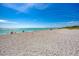 Expansive beach view featuring soft sand, calm turquoise waters, and a distant pier under a clear blue sky at 803 Carnoustie Dr, Venice, FL 34293