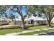 Charming home with verdant lawn, mature trees, manicured hedges, and a striking white tile roof at 803 Carnoustie Dr, Venice, FL 34293