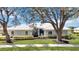 Charming single-story home with a well-manicured lawn, lush landscaping, and a pristine white tile roof at 803 Carnoustie Dr, Venice, FL 34293