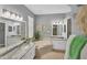 Well-lit bathroom features dual sinks, granite counters, a soaking tub, and decorative wall art at 805 Derbyshire Dr, Venice, FL 34285