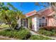 Entrance to home with immaculate landscaping, glass storm door, and bright windows at 805 Derbyshire Dr, Venice, FL 34285