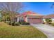 Beautifully landscaped single-story home with a pink two car garage, surrounded by greenery at 805 Derbyshire Dr, Venice, FL 34285