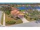 Charming single-story home featuring a tile roof, lush landscaping, and a serene lake view at 805 Derbyshire Dr, Venice, FL 34285