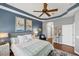 Comfortable bedroom with a blue accent, overhead fan, and stylish decor with beach themed paintings at 805 Derbyshire Dr, Venice, FL 34285