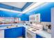 A modern kitchen features blue cabinets, a microwave, an electric stove, and a stainless steel sink at 811 Waterside Dr # 102, Venice, FL 34285