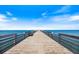 An eye-level shot of a pier with wooden railings under a blue sky, facing towards the ocean at 811 Waterside Dr # 102, Venice, FL 34285