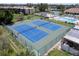 An aerial view of the well-maintained community tennis courts surrounded by lush landscaping and buildings at 811 Waterside Dr # 102, Venice, FL 34285