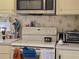 Fully equipped kitchen with white appliances and vintage wallpaper at 88 Bainbridge Dr # 88, Nokomis, FL 34275