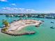 Stunning aerial view of an island with turquoise water, sandy beaches, and rock barriers under a sunny sky at 351 Carlino Dr, Nokomis, FL 34275