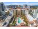 Aerial view of the condo building with a pool, manicured landscaping, and city skyline backdrop at 100 Central Ave # D509, Sarasota, FL 34236