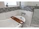 Close-up of a standalone soaking tub with wooden tray next to glass shower with white and gray tile at 100 Central Ave # D509, Sarasota, FL 34236