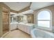 Bright bathroom featuring dual sinks, a soaking tub, a large window, and a separate glass shower at 1358 Ewing St, Nokomis, FL 34275