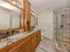 Bathroom with double sinks, granite counters, and a glass-enclosed shower at 17 Brentwood Ln, Englewood, FL 34223