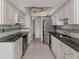 Galley kitchen featuring stainless steel appliances, granite countertops, and white cabinetry at 17 Brentwood Ln, Englewood, FL 34223