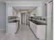 Galley-style kitchen featuring white cabinets, granite countertops, tile backsplash, and stainless steel appliances at 17 Brentwood Ln, Englewood, FL 34223