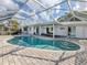 Backyard pool featuring a screened enclosure, lush landscaping, and a pristine pool area for relaxation and enjoyment at 17 Brentwood Ln, Englewood, FL 34223