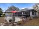 View of the rear exterior with a stone patio, red umbrella, grill and a screened in porch, ideal for outdoor living at 2537 Northway Dr, Venice, FL 34292