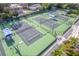 Aerial view of community tennis and pickleball courts, complete with shade covers and seating on a sunny day at 3 Inlets Blvd # 3, Nokomis, FL 34275