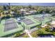 Overhead view of well maintained community tennis and pickleball courts with shade covers, surrounded by mature trees at 3 Inlets Blvd # 3, Nokomis, FL 34275