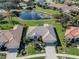 Aerial view showcasing a home with a pond view, lush lawn, and mature landscaping at 5071 Winter Rose Way, Venice, FL 34293