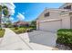 Home exterior featuring a two-car garage, well-kept lawn, and lush landscaping at 5371 White Ibis Dr, North Port, FL 34287