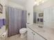 Clean bathroom with a vanity, mirror, tile floors, and a shower/tub with a patterned purple curtain at 564 Meadow Sweet Cir, Osprey, FL 34229