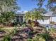 Charming single-story home featuring lush landscaping, including palm trees, shrubbery, and colorful flowers at 564 Meadow Sweet Cir, Osprey, FL 34229