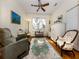 Brightly lit living room with light-colored wood floors, a ceiling fan, multiple seating options, and natural light at 564 Meadow Sweet Cir, Osprey, FL 34229