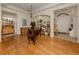 Spacious living room featuring hardwood floors, arched doorways, piano, artwork, and a decorative stained glass doorway at 564 Meadow Sweet Cir, Osprey, FL 34229