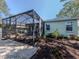 Backyard patio with a screened-in enclosure, landscaping, rock accents, a grill, and outdoor seating at 564 Meadow Sweet Cir, Osprey, FL 34229