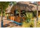 Outdoor tiki bar with thatched roof and bamboo fence seating area on a sunny day at 564 Meadow Sweet Cir, Osprey, FL 34229