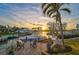 Picturesque waterfront view showcasing a private boat dock with boat, seating, and a beautiful sunset backdrop at 641 Bayshore Rd, Nokomis, FL 34275