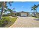 Charming single-story home with a circular brick paver driveway, lush lawn, and an American flag at 641 Bayshore Rd, Nokomis, FL 34275