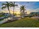 Scenic waterfront property featuring a private dock with a boat lift, lush landscaping, and stunning sunset views at 641 Bayshore Rd, Nokomis, FL 34275