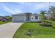 Single-story home with gray siding, attached garage, and landscaped lawn at 7057 Regina Dr, Englewood, FL 34224