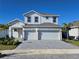 Two-story house with white exterior, two-car garage, and gray paver driveway at 9589 Vibrant Lane, Venice, FL 34292