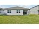 Home's rear view, showcasing a grassy yard and covered patio at 494 Sun Chaser Dr, Nokomis, FL 34275