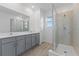 Bathroom with gray vanity, quartz countertop, and glass shower at 17355 Peregrine Way, Punta Gorda, FL 33982