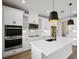 Modern kitchen with white cabinets, white quartz countertops, and stainless steel appliances at 101 Runaway Field Ave, Nokomis, FL 34275