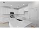 Modern kitchen boasts white cabinets, stainless steel appliances, and a large island with a sink at 9572 Vibrant Lane, Venice, FL 34292