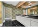 Double vanity bathroom with dark countertop and patterned wallpaper at 200 Colony Point S Rd, St Petersburg, FL 33705